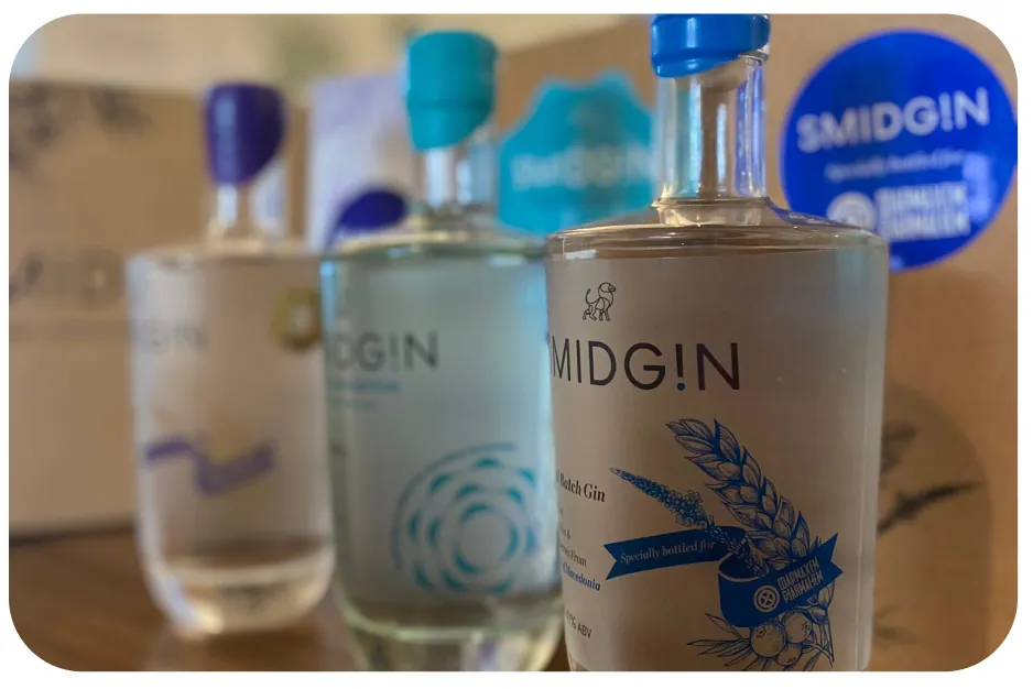Three Smidgin bottles with personalised labels and coloured wax caps, beside a branded gift box